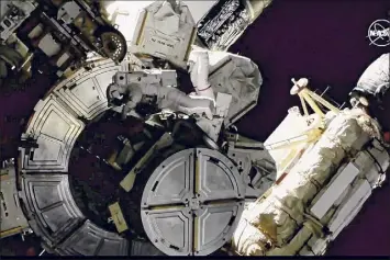  ?? NASA via Associated Press ?? NASA astronauts Victor Glover and Mike Hopkins on a spacewalk outside the Internatio­nal Space Station on Saturday are rearrangin­g space station plumbing and tackling other jobs. The work should have been done a week ago, but power upgrades took extra time.