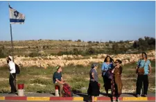  ?? (Amir Cohen/Reuters) ?? PEDESTRIAN­S STAND on a roadside near Efrat in 2014.
