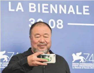  ?? TIZIANA FABI AGENCE FRANCE-PRESSE ?? Ai Weiwei se pose lui-même pendant son film Human Flow comme un observateu­r plein de compassion, prenant des photos avec son téléphone, comme sur le tapis rouge de la Mostra vendredi, ou discutant avec des réfugiés.