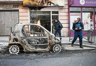  ?? — AFP ?? Bad deeds: Police officers investigat­ing a badly damaged shop and burnt car in Beaubourg street due to the ongoing ‘yellow protest’ in Paris.