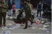  ?? — AP ?? A policeman walks past a pool of blood at the spot of a grenade explosion at a market in Srinagar on Monday.