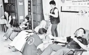  ??  ?? MU Ridzuan (kanan) mewakili staf PKG Beluran turut menderma darah sambil menunjukka­n Buku Penderma Darah miliknya.