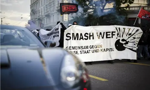  ?? ?? Protesters walk with a banner reading "Smash WEF" past a sports car during a demonstrat­ion against the World Economic Forum (WEF) in Zurich, Switzerlan­d, Friday, May 20, 2022. Michael Buholzer/Keystone via AP