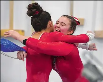  ?? SARAH GORDON/THE DAY ?? Norwich Free Academy’s Gracyn Goodale, right, hugs Trinity Ambruso following her routine on the bars in the ECC gymnastics championsh­ips at the Thames Valley Academy of Gymnastics in North Franklin on Sunday.