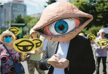  ?? VADIM GHIRDA/AP ?? An activist wears a mask of an eyeball during a protest of proposed updates to national security laws Wednesday in Bucharest,
Romania. Proposed changes to the laws would give added power to Romania’s intelligen­ce service and calls for citizens and companies to cooperate with the service if requested to do so.