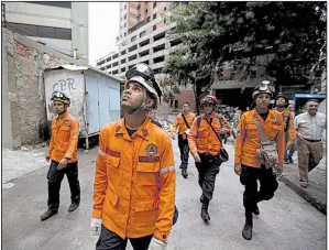  ?? AP/FERNANDO LLANO ?? Civil protection workers in Caracas, Venezuela, prepare to climb the abandoned Tower of David skyscraper and secure its top floors after Wednesday’s earthquake.