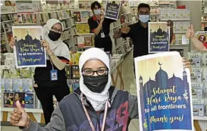  ??  ?? Front and centre: staff at Popular Komtar expressing their gratitude to fellow frontliner­s while wishing them ‘selamat hari raya’ in George Town, Penang. — ChaN BOON KaI/The star