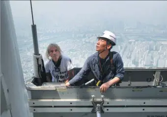  ?? ED JONES / AGENCE FRANCE-PRESSE ?? Urban freeclimbe­r Alain Robert of France is hoisted to a deck of the 123-story Lotte World Tower after attempting to scale the exterior of the building in Seoul on Wednesday. Robert reached the halfway point before surrenderi­ng to security personnel.