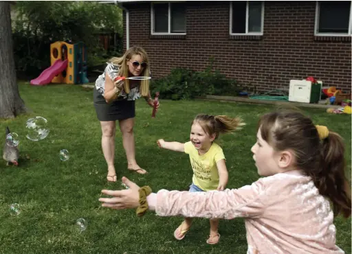  ?? Rachel Ellis, The Denver Post ?? Brittany Nidy blows bubbles Thursday for her daughters, Cora, 3, and Paisley, 7, at their home in Arvada. The family is likely to do online learning this upcoming school year.