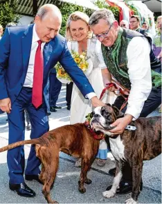  ??  ?? Tierlieb: Russlands Präsident Wladimir Putin streichelt die Boxerhunde der österrei chischen Ministerin Karin Kneissl und ihres Mannes Wolfgang Meilinger.