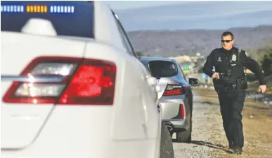  ?? STAFF PHOTO BY DOUG STRICKLAND ?? Officer Chris Mullinix returns to his car after giving a speeding citation to a driver on Interstate 75 while on traffic patrol Friday.