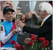  ?? (AP/Jeff Roberson) ?? Trainer Bob Baffert (right) hands the winner’s trophy to John Velazquez after the jockey rode Medina Spirit to victory in the 147th running of the Kentucky Derby on Saturday at Churchill Downs in Louisville, Ky. It was a record seventh Derby victory for Baffert and the fourth for Velazquez.