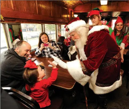  ?? NWA Democrat-Gazette/ANDY SHUPE ?? Olivia Scott of Springdale gets a high five from Santa Claus as her father Jason Scott watches during the 2016 “Children’s Christmas Train” at the Arkansas & Missouri Railroad depot in Springdale. The 2017 train will run Saturday to benefit the...