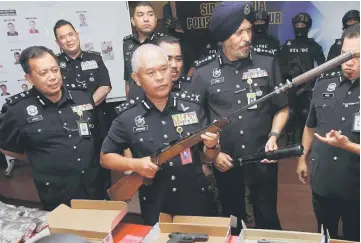  ??  ?? Mohmad Salleh (second left) shows a confiscate­d rifle at the press conference. — Bernama photo