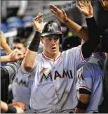  ?? MARK BROWN / GETTY IMAGES ?? Brian Anderson is greeted by Miami teammates after scoring in the third inning against Atlanta. Anderson leads major league rookies in several offensive categories.