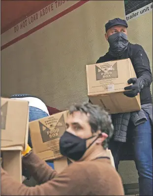  ??  ?? Volunteers unload boxes of food from a truck for the distributi­on program run.