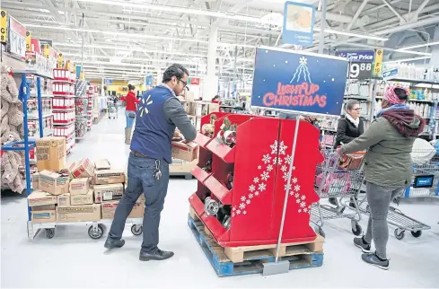  ?? REUTERS ?? ABOVE An employee works on a display ahead of Black Friday at a Walmart store in Chicago, Illinois on Tueday.