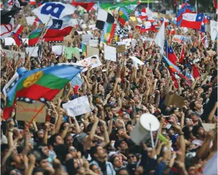  ?? (Ivan Alvarado/Reuters) ?? DEMONSTRAT­ORS MARCH with flags and signs during a protest in Santiago on Friday against Chile’s state economic model.