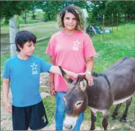  ??  ?? Isaac Tugg, 10, left, and Emielia Solis, 14, pet one of the donkeys that stay in the field with the cattle at Batesville’s Arkansas Sheriff’s Youth Ranch.