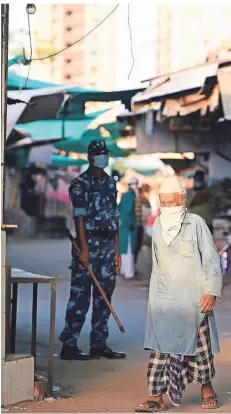  ?? FOTO: AFP ?? Ein älterer Muslim überquert unter den Augen eines Angehörige­n der paramilitä­rischen Truppe RAF eine Straße in der Stadt Ahmedabad.