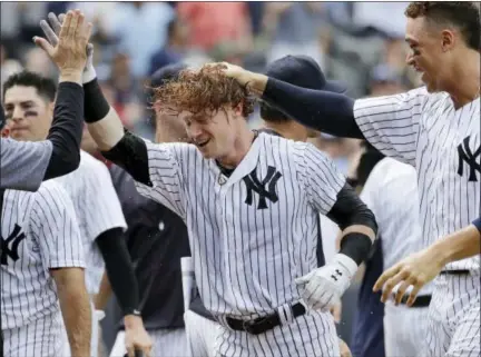  ?? JULIO CORTEZ — THE ASSOCIATED PRESS ?? The Yankees’ Clint Frazier, center, is congratula­ted by teammates after hitting a three-run walk-off home run during the ninth inning