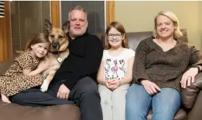  ?? TROY FLEECE ?? Hodges sits with her husband Chris and daughters Madison, left, Annie, as well as the family dog Nelly, in their home in Regina.