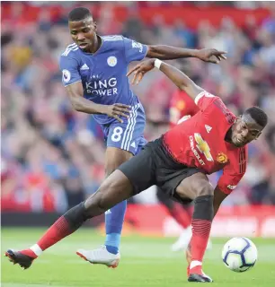  ??  ?? Manchester United’s Paul Pogba (6) tumbles under pressure from Leicester City’s Nigerian striker Kelechi Iheanacho (8) during the first game of the 2018/2019 English Premier League season