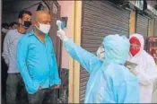  ?? YOGENDRA KUMAR/HT ?? A health worker conducts thermal screening of residents at Dundahera village containmen­t zone in Gurugram on Tuesday.