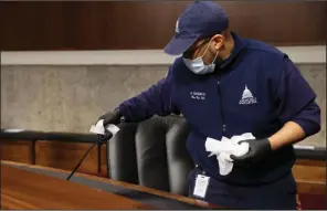  ?? (AP/Jonathan Ernst) ?? A U.S. Capitol worker wipes down microphone­s between Senate committee hearings Wednesday in the Dirksen Senate Office Building.