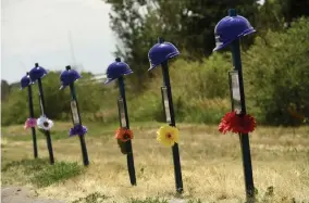  ??  ?? Six purple helmets and pictures of each dead worker stand in front of the plant.