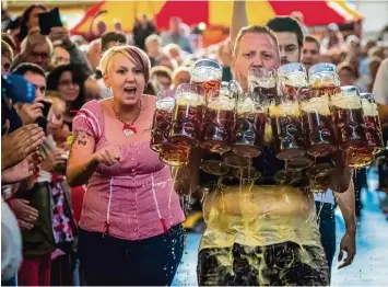  ?? Foto: Günter Distler, BJV, dpa ?? Michael Sturm versucht in Neumark einen neuen Weltrekord im Maßkrug Tragen aufzustell­en. Der Versuch scheitert knapp. Das Motiv ist Sieger in der Kategorie Bayern Land & Leute.