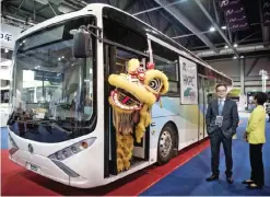  ?? — AFP ?? HONG KONG: A performer wearing a lion dance costume stands at the door of an electric bus during the opening of the China Internatio­nal New Energy Vehicle (CINEV) show in Hong Kong.