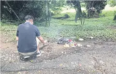  ??  ?? A man makes an offering for his ancestor at Bukit Brown cemetery. As developmen­t encroaches, more graves are being dug up and the remains cremated after consultati­on with descendant­s of the deceased.