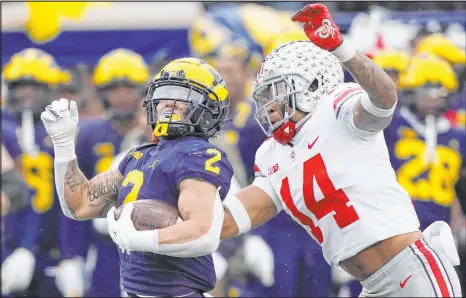  ?? Carlos Osorio The Associated Press ?? Something has to give when Michigan running back Blake Corum, Ohio State safety Ronnie Hickman and their teams put perfect marks on the line Saturday.