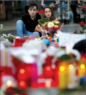  ?? AP/MANU FERNANDEZ ?? A couple in Barcelona, Spain, look over a memorial of flags, messages and candles Saturday at the scene of Friday’s terrorist attack, when a van driver killed at least 13 people.