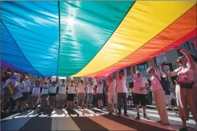  ?? Associated Press photo ?? Marchers unfurl a huge rainbow flag as they prepare to march in the Equality March for Unity and Pride in Washington, Sunday.