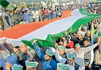  ?? — PTI ?? Farmers hold a tricolor to protest against the new farm laws at Ghazipur in New Delhi on Sunday.