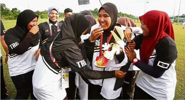  ??  ?? Centre of attraction: Terengganu’s nur Aqilah yusof (centre) is mobbed by team-mates after winning the gold medal in the 70m recurve at the unimas Campus in Kota Samarahan yesterday.