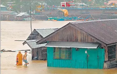  ??  ?? Residents walk past flooded houses in Tandag City, Surigao del Sur province, on Mindanao island. The Philippine­s have moved over 51,000 people to safer grounds as the approachin­g tropical storm Dujuan flooded parts of the southern and central parts of the country, a government disaster agency said on Sunday.