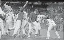  ?? MATT SLOCUM Associated Press ?? TREVOR PLOUFFE, second from right, is mobbed by teammates after hitting a walkoff, three-run home run in the 16th.