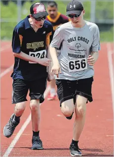  ?? CLIFFORD SKARSTEDT EXAMINER ?? Holy Cross Hurricanes’ Braden Fallis is encouraged by Ben Sunderland in a 400-metre race during the 2018 Special Olympics Ontario School Championsh­ips on Wednesday at the Thomas A. Stewart track.