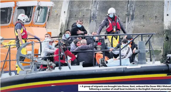  ??  ?? > A group of migrants are brought into Dover, Kent, onboard the Dover RNLI lifeboat following a number of small boat incidents in the English Channel yesterday