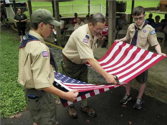  ?? DAVID MEKEEL — MEDIANEWS GROUP ?? Boys Scouts Cole Peifer, left, and Gavin Bortz hold a flag while their scoutmaste­r Geroge Statzell cuts it to prepare the flag for retirement.