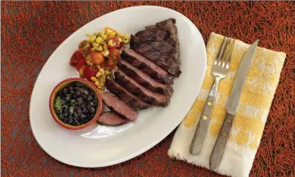  ?? THE ASSOCIATED PRESS ?? Skirt steak with beer-braised black beans and corn salsa.