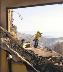  ?? Kent Nishimura Los Angeles Times ?? A FIREFIGHTE­R works to extinguish hot spots amid structures destroyed by the Woolsey fire this week in Bell Canyon.