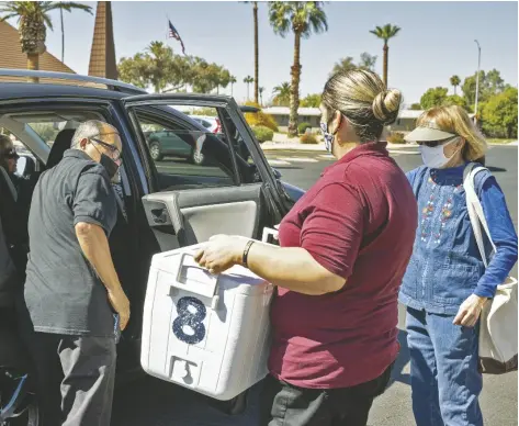  ?? FOTO MONSERRAT APUD, CRONKITE NOTICIAS ?? CHERYL DUTER, presidenta del capítulo de Sun City de Meals on Wheel, a la derecha, dirige a Mauricio Díaz y Jovita Torres mientras cargan autos con comidas empaquetad­as el 24 de marzo de 2022 en Sun City.