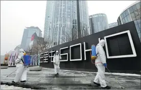  ?? ZHANG WEI / CHINA DAILY; ZOU HONG / CHINA DAILY; WEI XIAOHAO / CHINA DAILY ?? Top: People’s Liberation Army soldiers patrol Tian’anmen Square in Beijing. staff members disinfect a road outside the National Stadium.