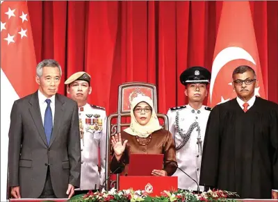  ?? WALLACE WOON/REUTERS ?? MOMEN BERSEJARAH: Halimah Yacob diambil sumpahnya sebagai presiden didampingi PM Lee Hsien Loong (kiri) dan Ketua MA Sundaresh Menon (kanan) kemarin. Dia menjadi perempuan pertama yang menduduki posisi tersebut.