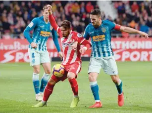  ?? — AFP ?? Atletico Madrid’s Koke (right) challenges Girona’s Cristian Portugues (centre) during the Spanish league match in Girona on Sunday.