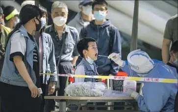  ?? Mark Schiefelbe­in Associated Press ?? A CHILD takes a coronaviru­s test in Beijing. Residents are required to undergo three tests during the week as authoritie­s seek to detect and isolate cases. A negative result is required for entry to most public spaces.